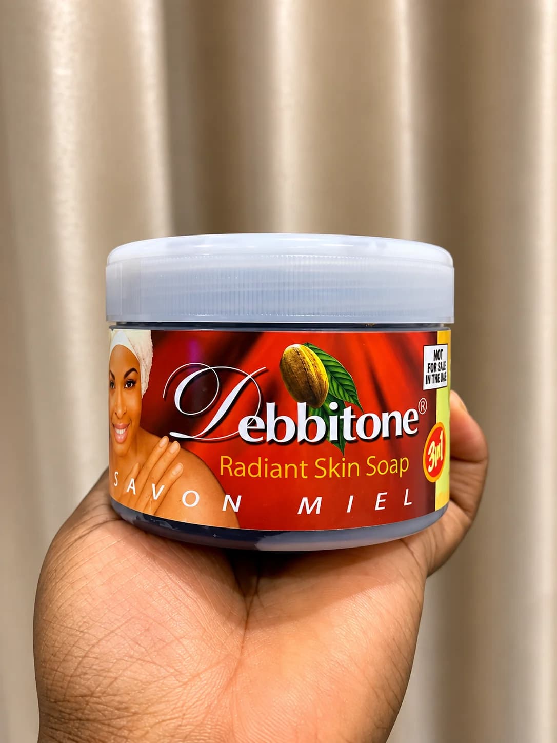 A 300g tub of Debbitone Radiant Skin Soap held in one hand